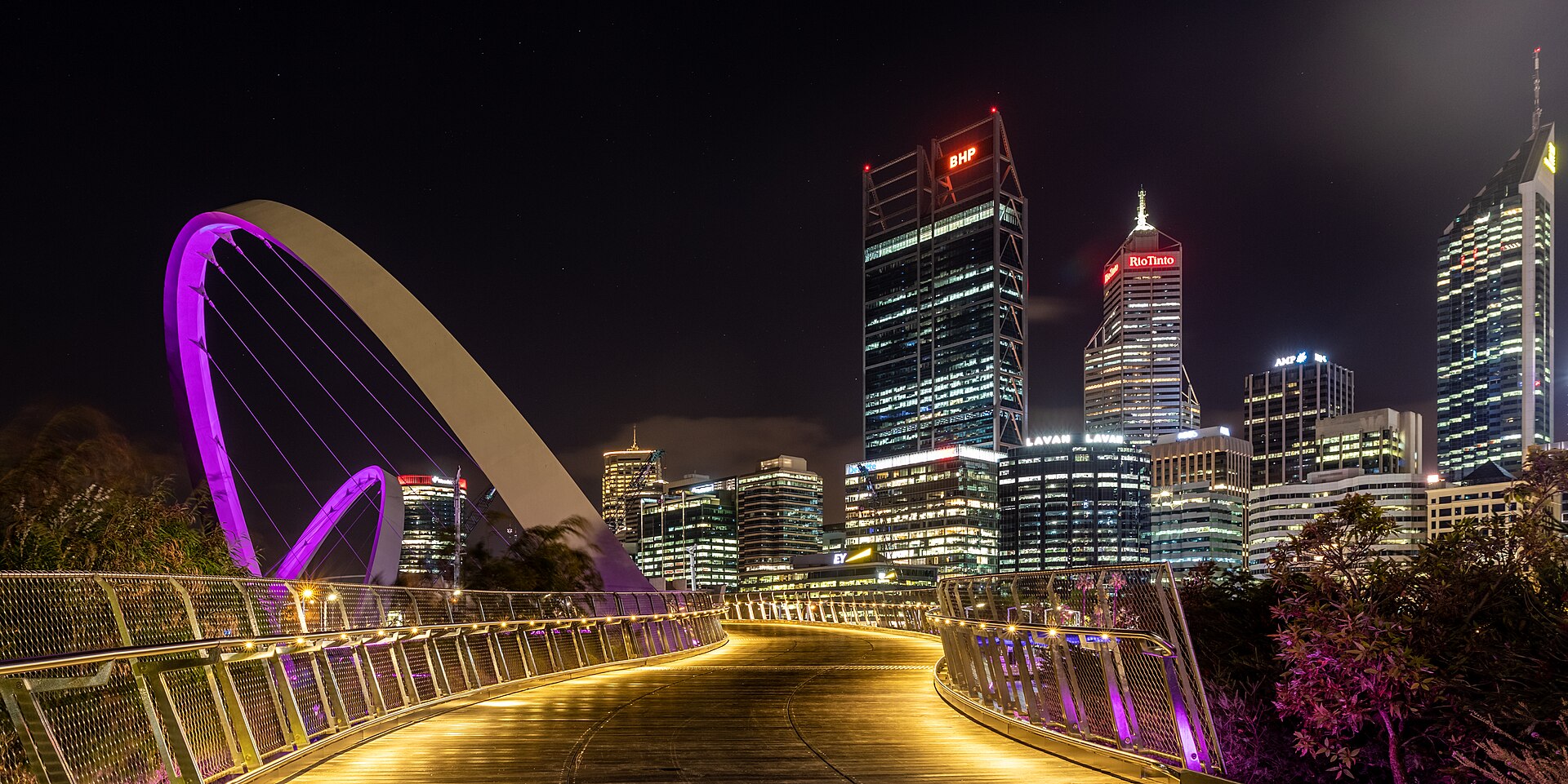 Elizabeth Quay Bridge, Perth, Western Australia, AustraliaThe Elizabeth Quay Bridge is a striking pedestrian bridge in Perth city center. It was built as part of the Elizabeth Quay urban development project, which aimed to strengthen the connection between the city center and the Swan River. The bridge opened in 2016.Its curved, asymmetrical design is characteristic. Two sloping steel arches support the structure and give it a dynamic, modern shape. With a length of around 110 meters, it spans a side arm of the Swan River and connects the promenade with the island in the harbour basin.The bridge is intended exclusively for pedestrians and cyclists and offers views of the Perth skyline. In the evening, it is illuminated and is a popular photo motif. The Elizabeth Quay Bridge symbolizes the urban renewal of the waterfront area and the opening of the city to the water.
